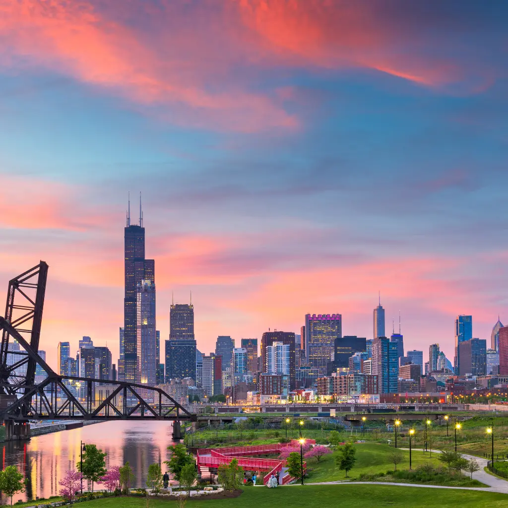 A breathtaking view of Illinois, the Land of Lincoln, showcasing the Chicago skyline at sunset with vibrant skies, a riverfront, and iconic skyscrapers. Transportvibe