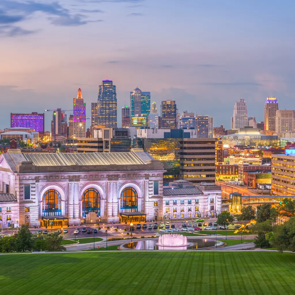 Kansas City skyline at dusk with Union Station and city lights glowing. Transportvibe