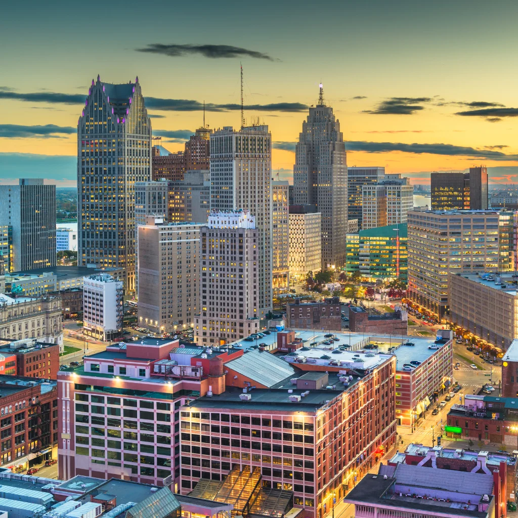 Detroit skyline at dusk with illuminated buildings and a colorful sky. michigan \ Transportvibe