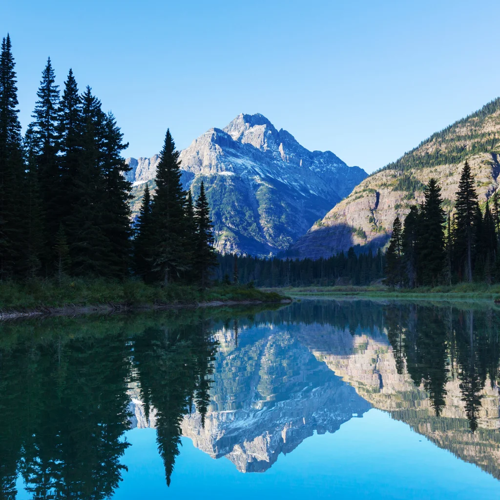 Glacier National Park in Montana with a mountain reflecting on a calm lake. Transportvibe