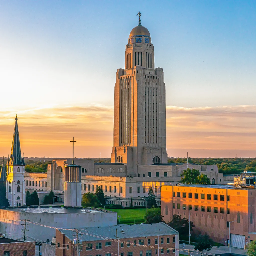 Nebraska State Capitol in Lincoln at sunset with a golden sky. Transportvibe