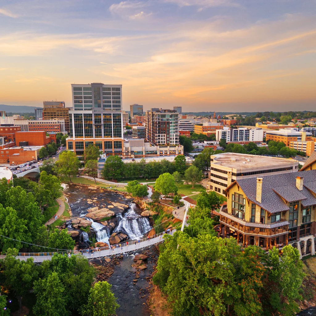Downtown Greenville, South Carolina, with waterfalls and modern buildings at sunset. Transportvibe